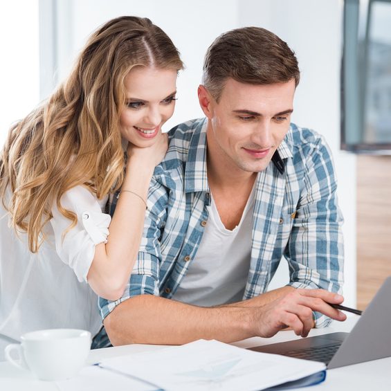 Beautiful couple using laptop and working together at home