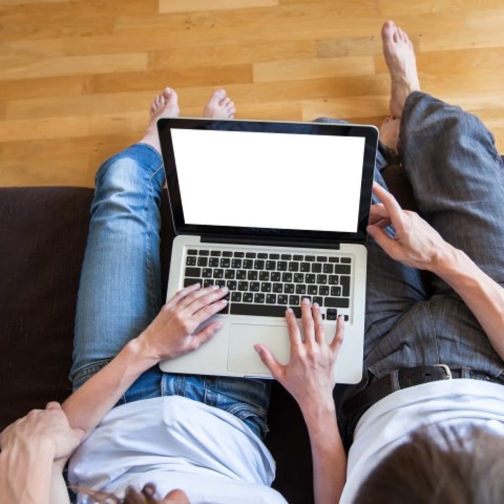 Couple sat on a sofa with a laptop on their laps.=, image shot from above.